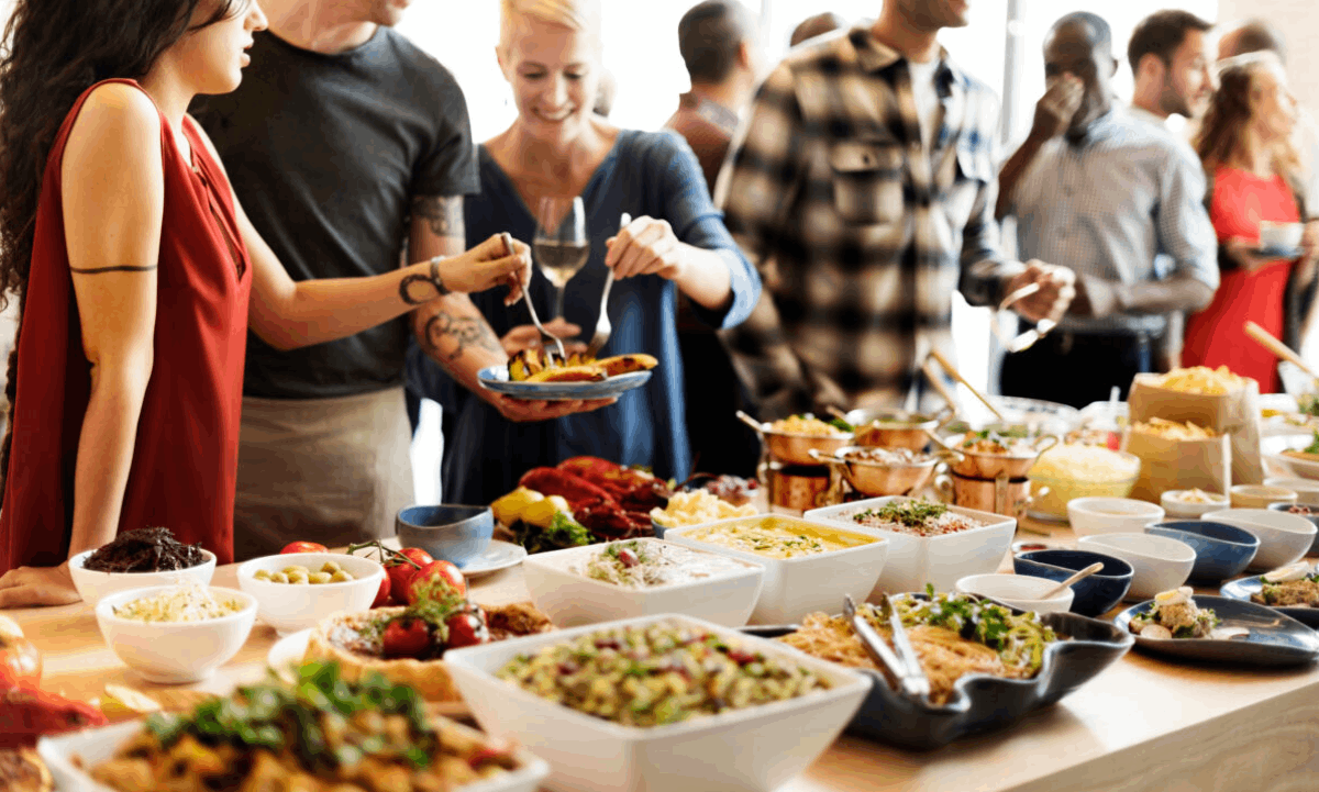A group of people gathered around a buffet table, serving food and sharing a meal together.
